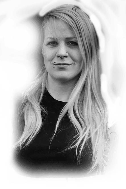 Portrait of tattoo artist Kirsti with long blonde hair and nose and lip piercings, black-and-white photo, Ink21 Vienna