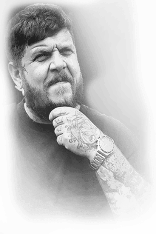 Tattoo artist Rares with a beard, tattooed hand on his chin, black-and-white portrait, Ink21 Tattoo Studio Vienna