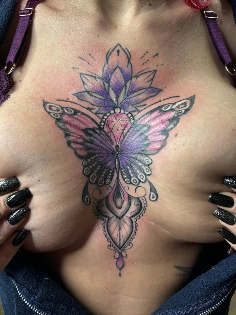 Colour ornamental sternum tattoo: a purple and pink butterfly with a lotus flower and mandala elements, tattoo Vienna