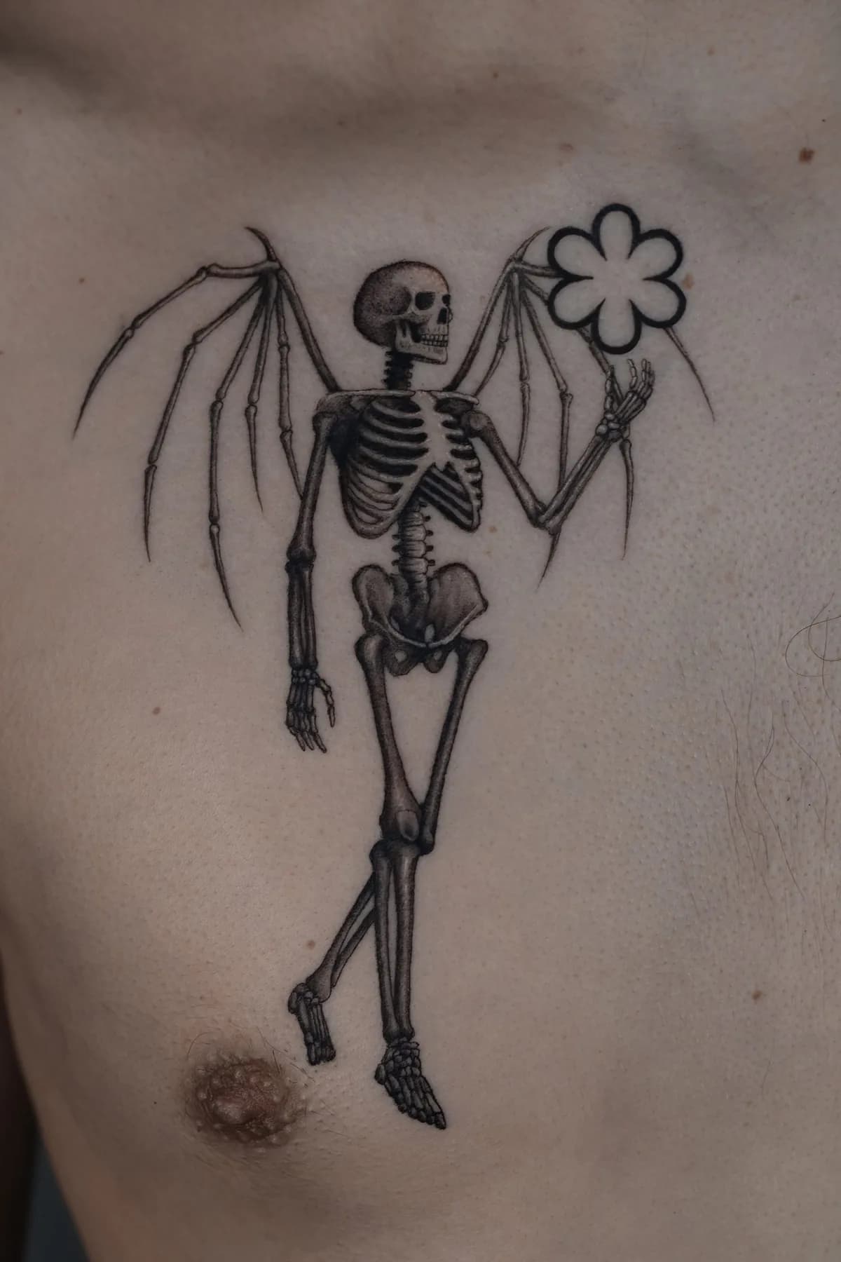 Winged skeleton holding a flower. Tattoo at Ink21 in Vienna.