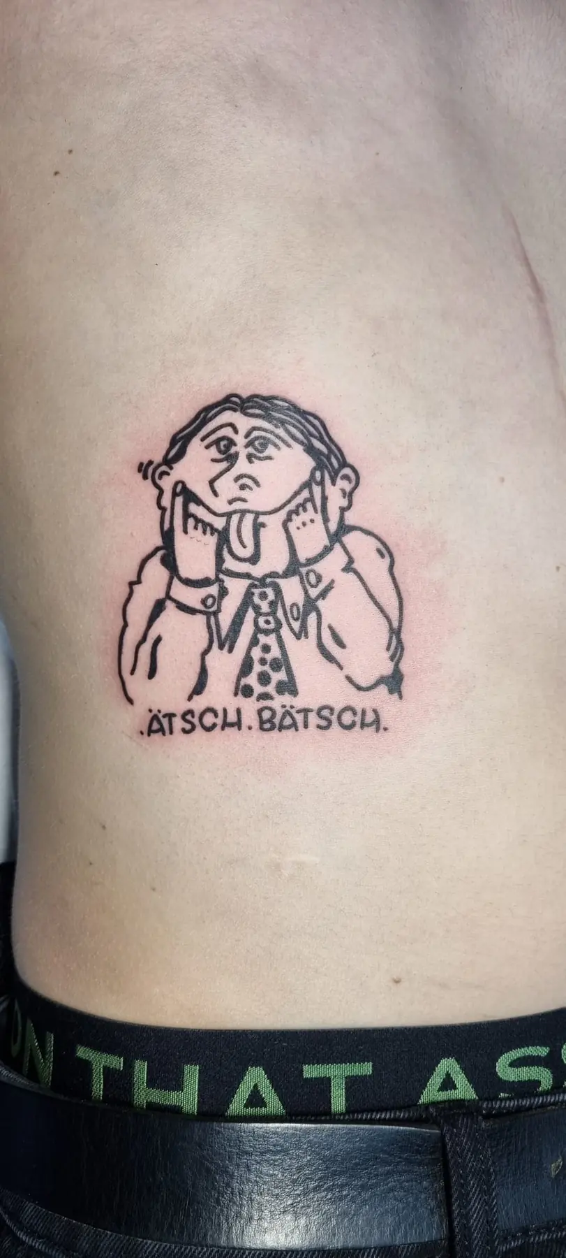 Small comic figure with a line of text. Tattoo at Ink21 in Vienna.