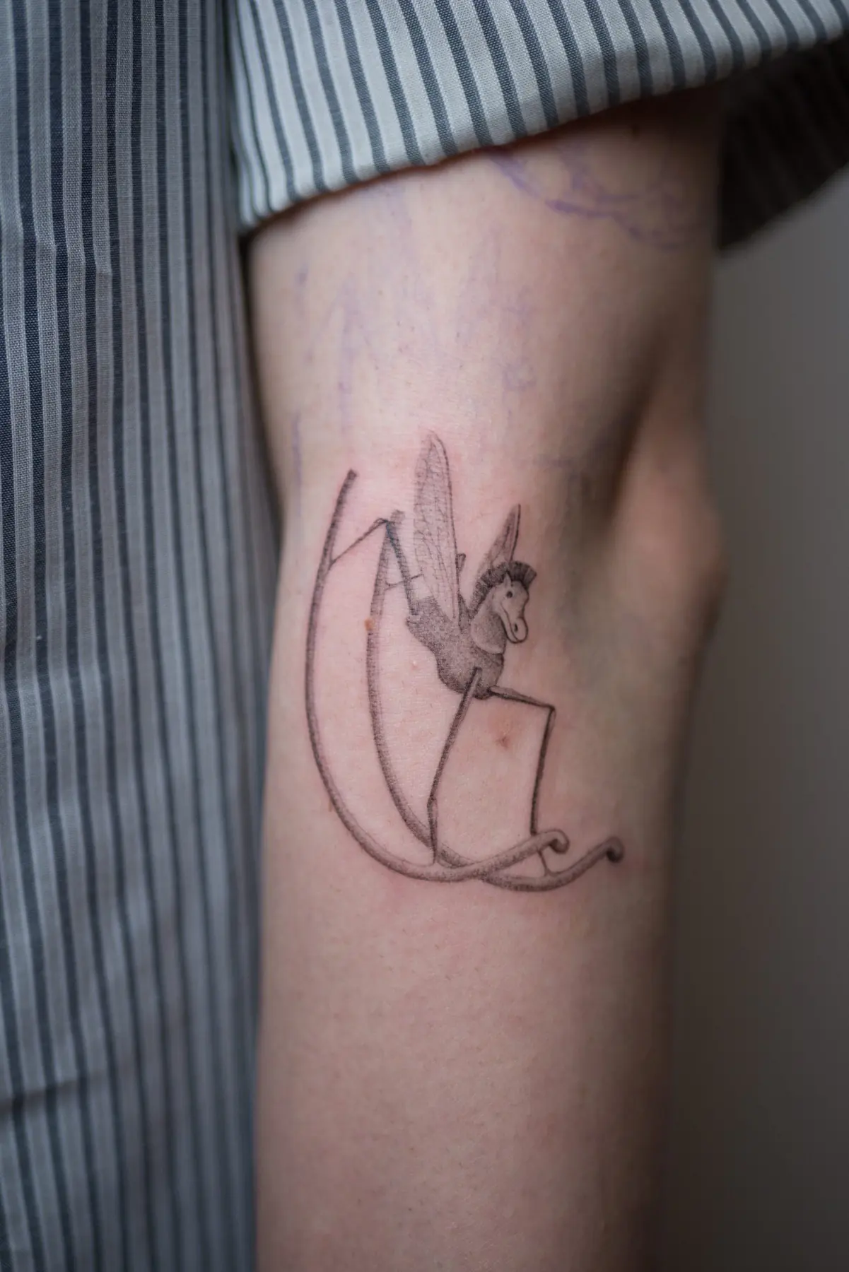 Small winged figure on a crescent. Tattoo at Ink21 in Vienna.