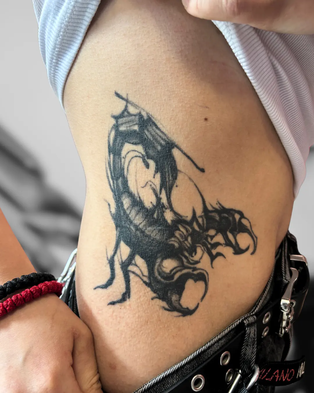 Black hip dragon with a coiled tail. Tattoo at Ink21 in Vienna.