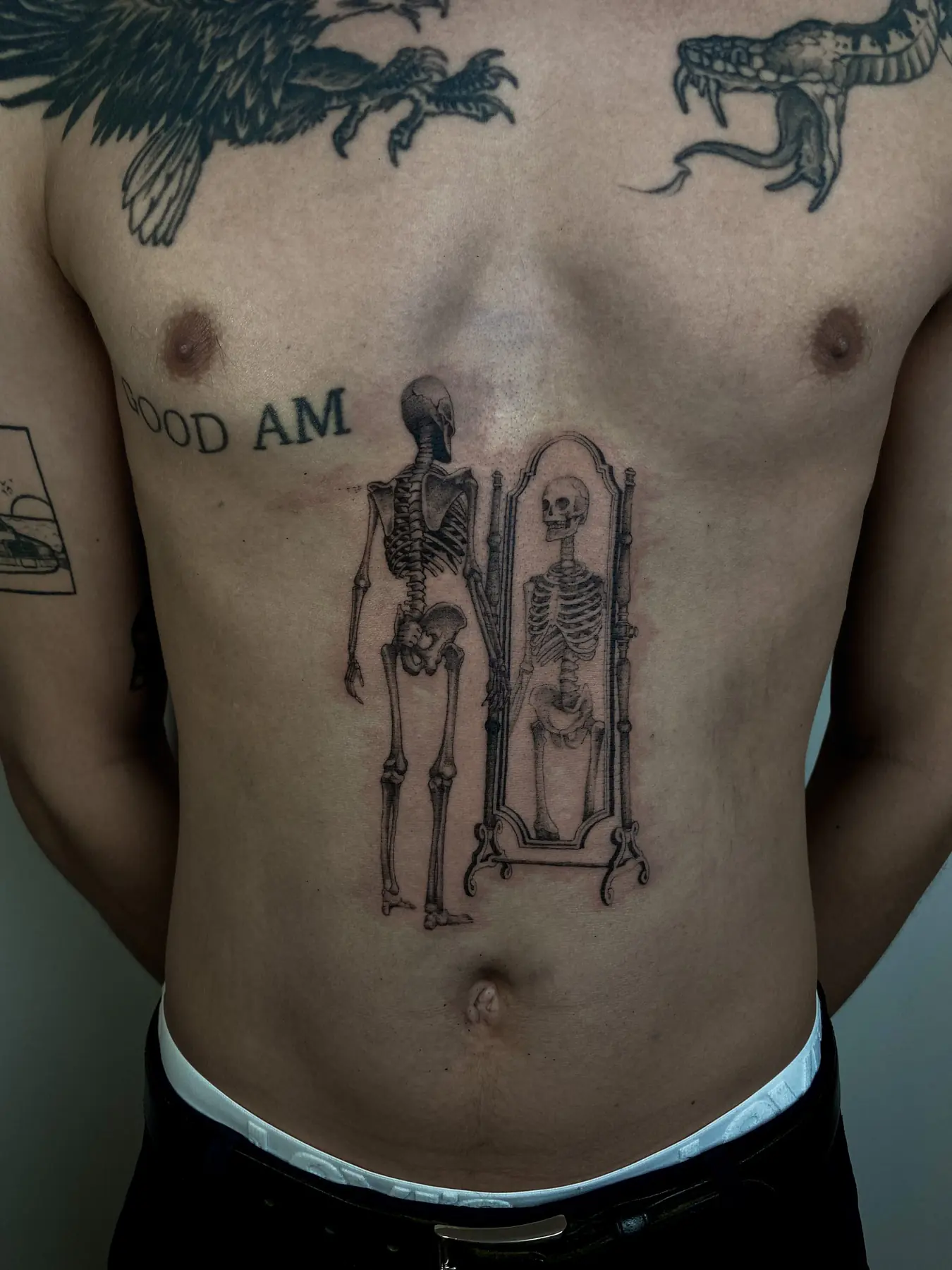 Skeleton facing a mirror on the torso. Tattoo at Ink21 in Vienna.