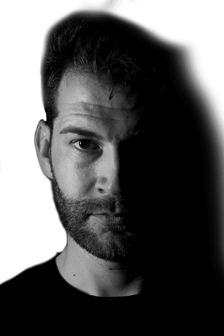 Portrait of tattoo artist Tibi with a beard, half his face in shadow, black-and-white photo, Ink21 Tattoo Studio Vienna