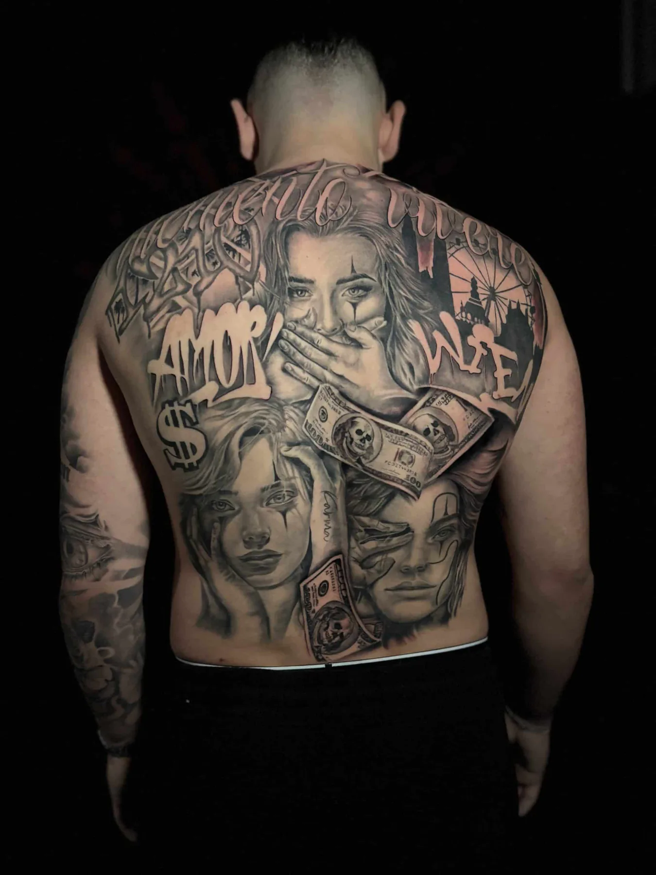 Chicano black and grey back tattoo with clown-faced women, banknotes, the word "Amor" and Vienna's Giant Ferris Wheel