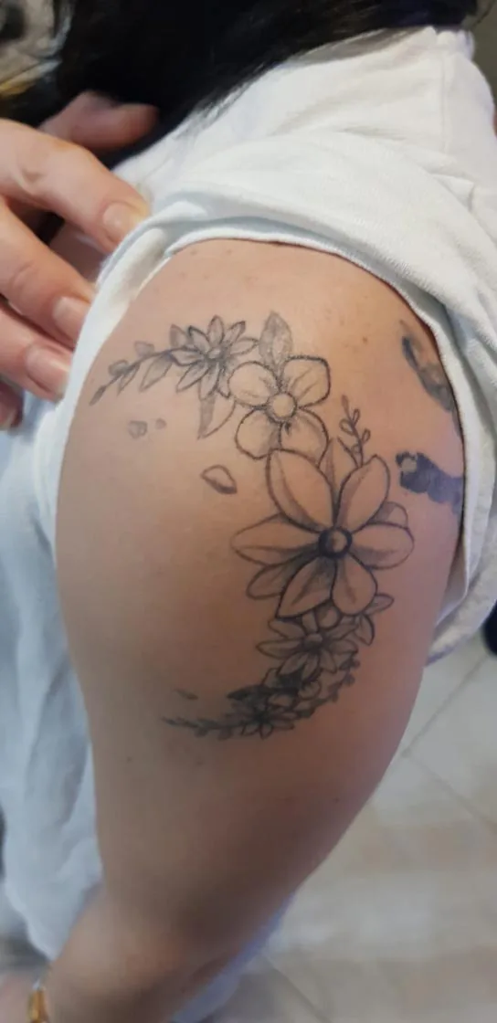 Curved flowers along the hip. Tattoo at Ink21 in Vienna.