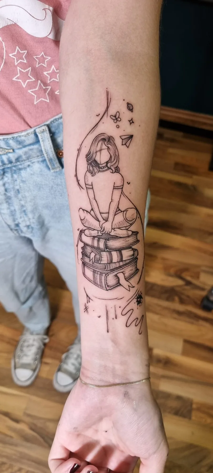 Stack of books with a seated figure. Tattoo at Ink21 in Vienna.