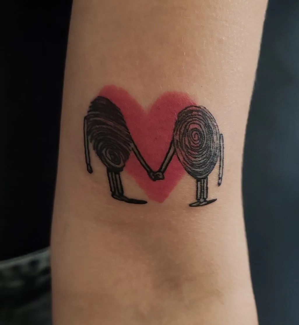 Fingerprint figures in front of a red heart. Tattoo at Ink21 in Vienna.