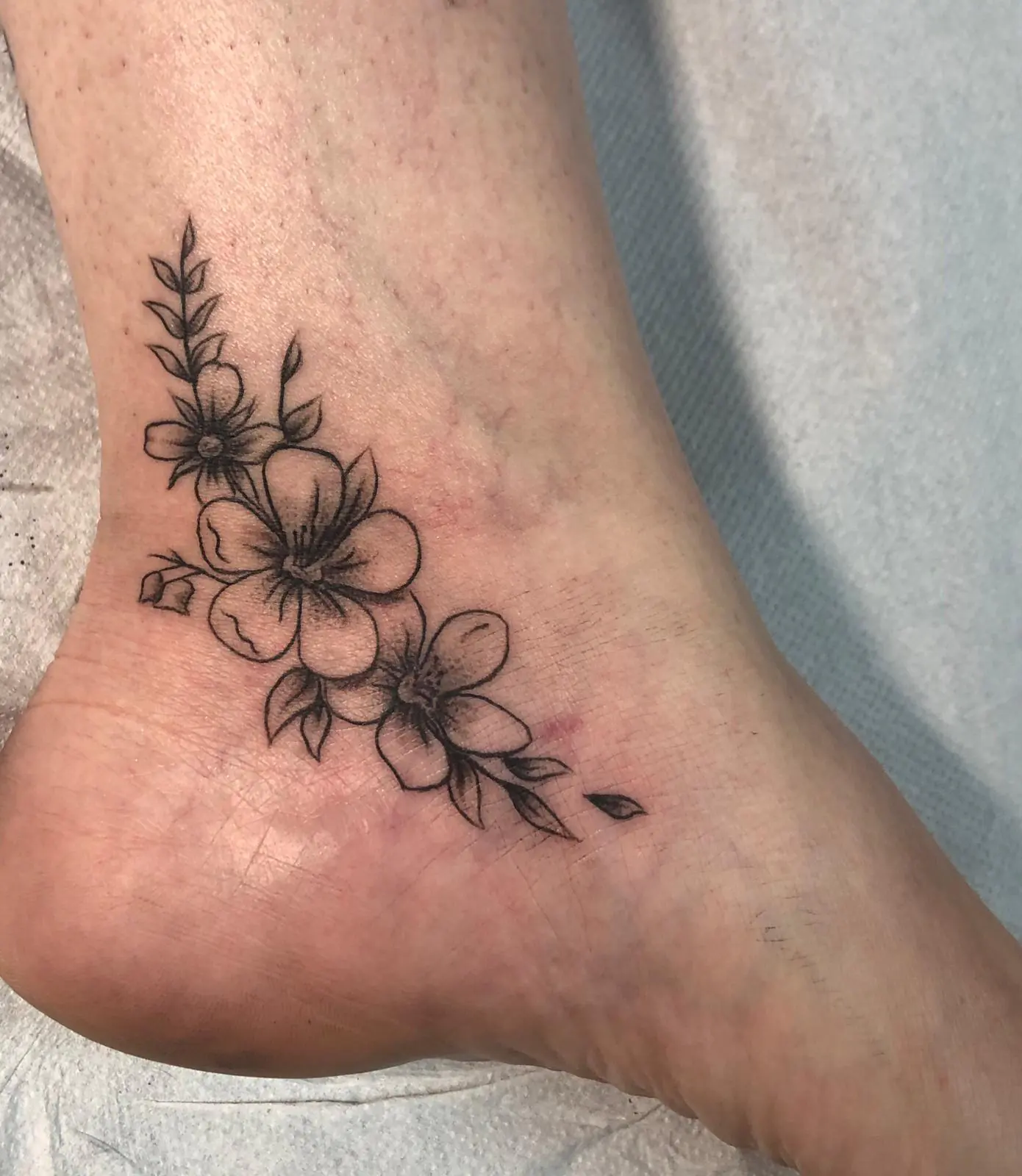 Small flowering branch at the ankle. Tattoo at Ink21 in Vienna.