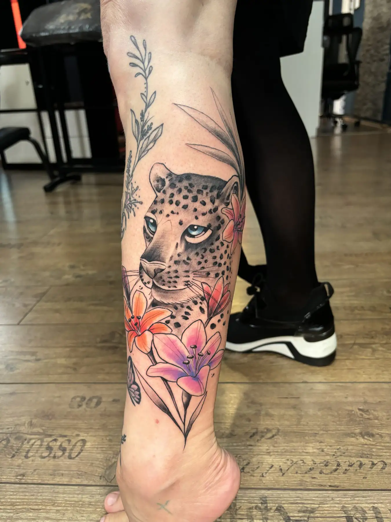 Leopard’s head with a floral frame on the leg. Tattoo at Ink21 in Vienna.