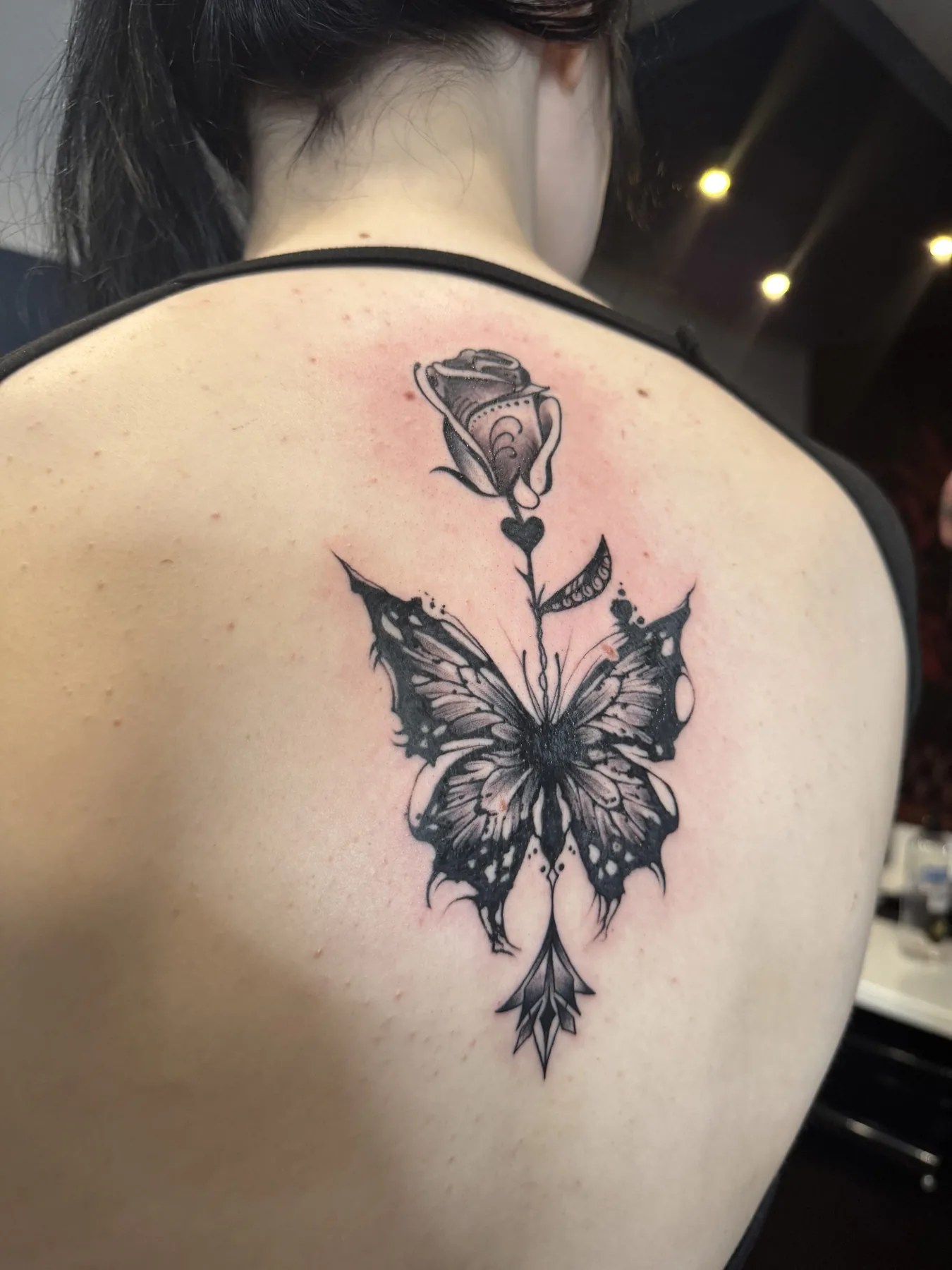 Butterfly beneath a back rose. Tattoo at Ink21 in Vienna.