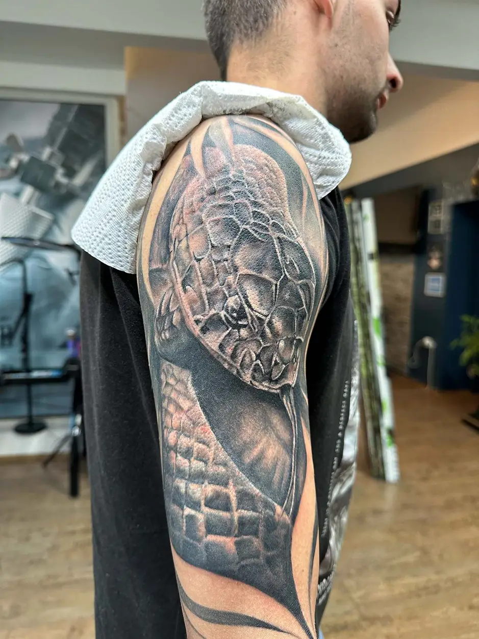Scaled creature’s head on the outer arm. Tattoo at Ink21 in Vienna.