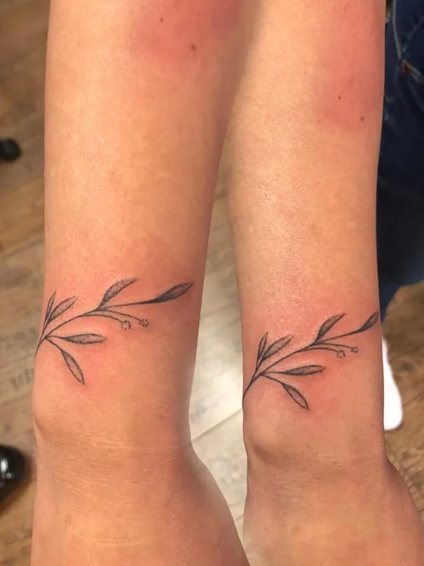 Two delicate leafy branches at the ankles. Tattoo at Ink21 in Vienna.